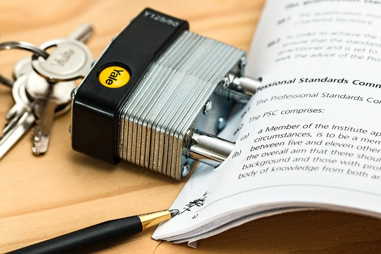 Close-up of a secured contract with a padlock and keys resting on signed legal documents on a wooden surface.