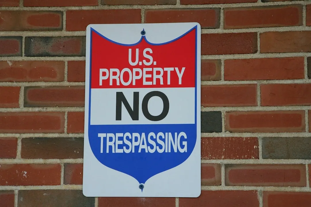 U.S. Property No Trespassing sign mounted on a red brick wall warning against unauthorized entry.
